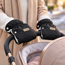 Sorte barnevognshandsker monteret p� barnevognens h�ndtag og anvendt med h�nderne i handskerne.