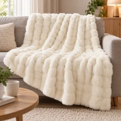 Hvidt fluffy t�ppe lagt over en sofa som bl�d plaid i en lys stue.
