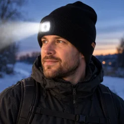 N�rbillede af LED-lygten foran p� den sorte strikhue med synlig knap og strikket tekstur.