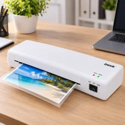 A4-lamineringsmaskine i brug p� et skrivebord med et strandfoto f�rt gennem maskinen.