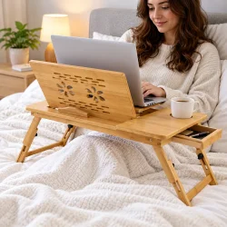 Laptopbord til seng i brug med b�rbar computer, justerbar bordplade, kopholder og skuffe.
