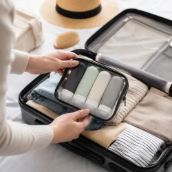 Toilettaske med rejseflasker til h�ndbagage pakket i kabinekuffert under flyrejse
