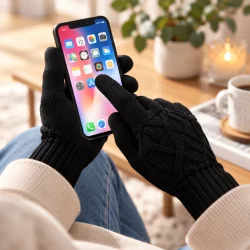 Sorte touchscreen-handsker i brug til betjening af en smartphone i hjemlige omgivelser.
